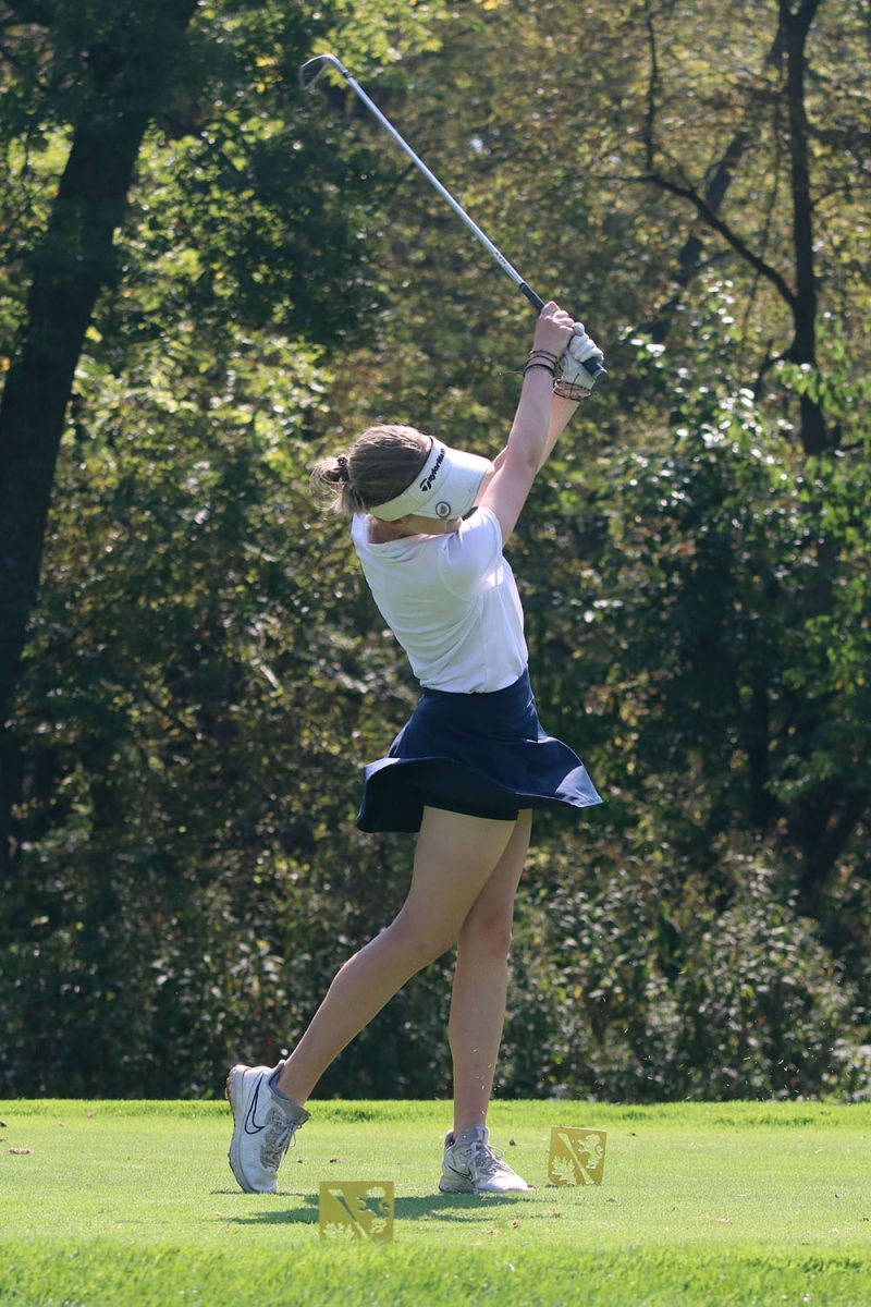 While swinging her club, junior Reagan Swartz hits the ball at hole 2.